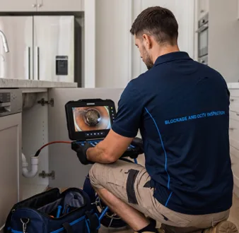 Plumber clearing a blocked toilet in a Marrickville bathroom